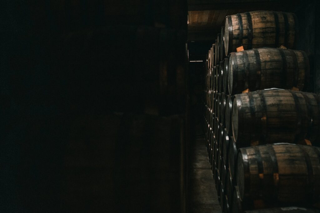 Barrels stacked in a dark warehouse representing scalable distribution and durable brand value
